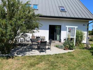a patio with chairs and a table in front of a house at Dom w Trawach in Smołdziński Las +15 photos