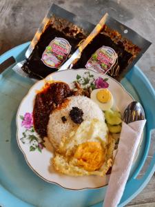 un plato de comida con huevos y pastel. en Ghumoh Safar (Bed,Pool & Cafe), en Kuala Kangsar