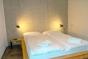 Una cama con sábanas blancas y toallas. en Eiger, en Spiez