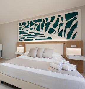 una camera da letto con un grande letto bianco con asciugamani di Residence Le Piscine a San Vito lo Capo