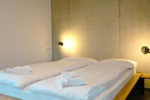 2 camas con sábanas blancas y toallas. en Eiger, en Spiez