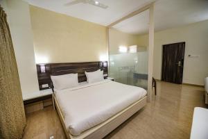 a bedroom with a white bed and a glass wall at Avenue 11 Premium Stays Madurai in Madurai