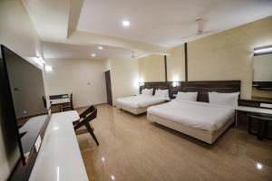 a hotel room with two beds and a television at Avenue 11 Premium Stays Madurai in Madurai