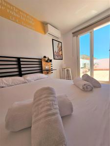 a bedroom with a large white bed with towels on it at Apartamentos Plaza Santo Domingo in Cádiz