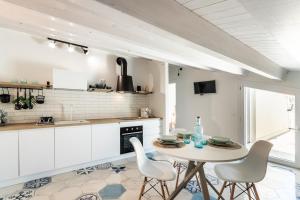 eine Küche mit weißen Schränken sowie einem Tisch und Stühlen in der Unterkunft House & Villas - Boutique Apartments in Avola