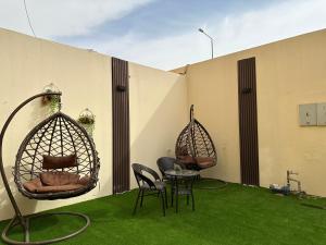 two chairs and a table on a patio with grass at شقة بمدخل خاص وجلسة خارجية ودخول ذاتي in Riyadh