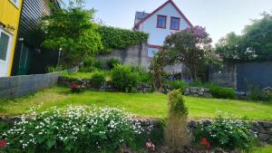 a garden with white flowers in front of a house at Heart of the City (Hotel Bólið Guesthouse) in Tórshavn