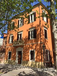 an orange building with a tree in front of it at Vittorio Veneto 25 in Modena