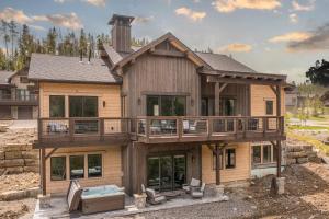 a house with a wrap around deck with a hot tub at Spanish Peaks Highlands Cabin 59 in Big Sky