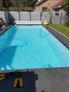 a large blue swimming pool in a yard at NamaStee aan Zee in Vlissingen