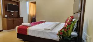 una camera da letto con un letto, una televisione e fiori di HOTEL PIONEER PARADISE a Nagercoil