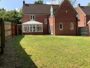 une maison avec une clôture et une cour d'herbe dans l'établissement Large Executive 4-Bed Detached House in Miskin, Cardiff-sleeps up to 10, à Hensol