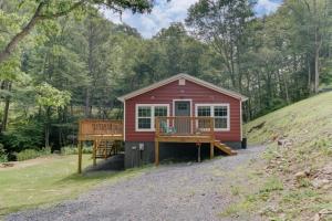 una casita roja pequeña con porche y terraza en Creekside Cottage, en Hot Springs