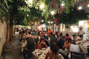 a group of people sitting at tables in a restaurant at Apergis Rooms in Ermoupoli