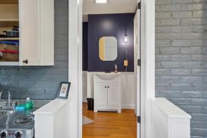 a kitchen with white cabinets and a sink and a brick wall at Kingston Crawfish Cottage Near Catskills! in Kingston