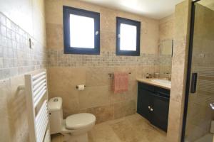 a bathroom with a toilet and a sink and two windows at La Lézarde, chambre d'hôte, piscine, salle d'eau privatif, café ou thé offert le matin in Saint-Victor-la-Coste