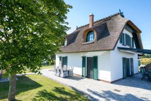 a cottage with a thatched roof and a patio at Ferienhaus Veronika an der Üselitzer Wiek in Mellnitz