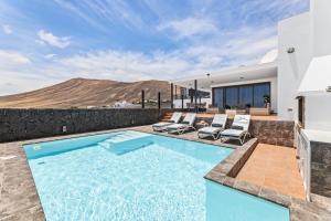 a swimming pool with chairs and a house at Villa con piscina climatizada y vistas al mar in Mácher
