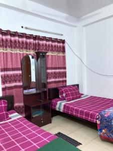 a room with two beds and a mirror at Mohammadia Restaurant & Guest House Near United Hospital in Dhaka