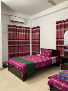 a bedroom with two beds and red curtains at Mohammadia Restaurant & Guest House Near United Hospital in Dhaka