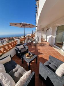 a balcony with couches and a table and an umbrella at Elegant apartment with fantastic views At the top of Calahonda in Sitio de Calahonda