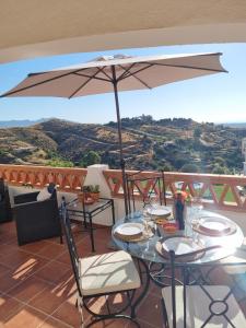 a table and chairs with an umbrella on a balcony at Elegant apartment with fantastic views At the top of Calahonda in Sitio de Calahonda