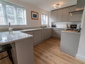 a kitchen with white cabinets and a wooden floor at Pass the Keys Beautiful Nottingham home with Private Driveway in Nottingham