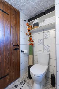 a bathroom with a toilet and a vase with flowers at Rock and Sea View House in Sitia
