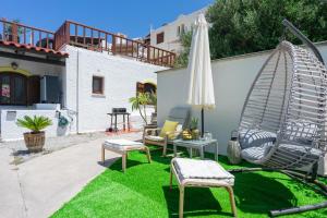 a patio with a hammock and an umbrella and grass at Rock and Sea View House in Sitia