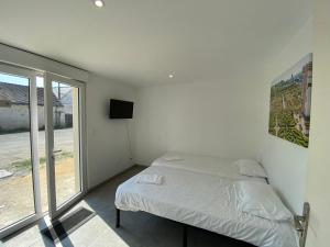 a white bedroom with a bed and a window at Appartement 8pers à Vallères in Vallères
