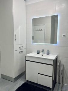 Baño blanco con lavabo y espejo en Apartamento familiar Praia Barra, en Praia da Barra