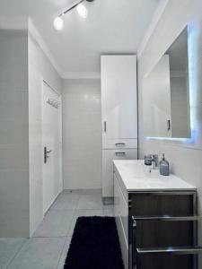 Baño blanco con lavabo y espejo en Apartamento familiar Praia Barra, en Praia da Barra