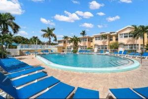 a large swimming pool with blue chairs and palm trees at Beach Condo in Clearwater Beach