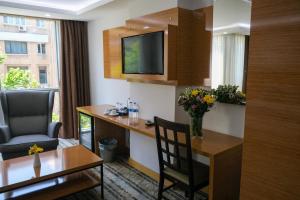Zimmer mit einem Schreibtisch, einem Stuhl und einem TV in der Unterkunft Bulvar Hotel in Izmir