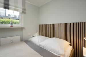 Schlafzimmer mit einem Bett mit weißer Bettwäsche und einem Fenster in der Unterkunft Waldstraße 8 Wohnung 1 in Kellenhusen