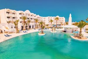 Djerba的住宿－Best Time Alkantara Djerba，棕榈树和建筑度假村内的游泳池