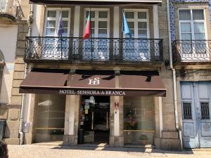 un edificio con 2 banderas en un balcón en Hotel Senhora A Branca, en Braga