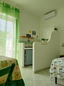 Dieses weiße Zimmer verfügt über einen Tisch und eine Küche. in der Unterkunft Il monolocale verde conchiglie e fiori in Ponza