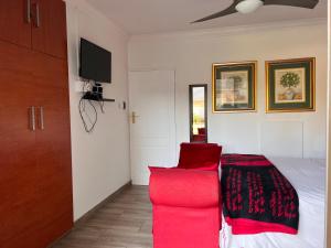 a bedroom with a bed and a red couch at 2 Op Terblanche Guesthouse in Boksburg