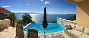a swimming pool with chairs and an umbrella on a patio at Villa Sabine Apartment Losinj in Medveja