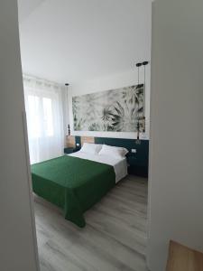 una camera con letto e copriletto verde di Corso Matteotti 162 - Affittacamere a Porto Recanati