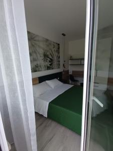 a bedroom with a bed with a green and white blanket at Corso Matteotti 162 - Affittacamere in Porto Recanati