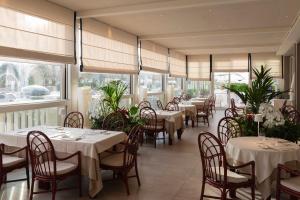 a restaurant with white tables and chairs and windows at Grand Hotel & Riviera in Lido di Camaiore