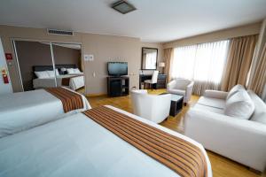 a hotel room with two beds and a living room at Amérian Cordoba Park Hotel in Córdoba