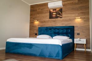 ein Schlafzimmer mit einem blauen Bett und einer Holzwand in der Unterkunft Havana Resort in Murighiol