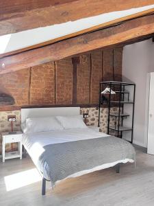 Cama grande en habitación con pared de ladrillo en Apartamentos Numancia en Garray