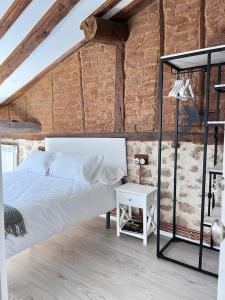 a bedroom with a white bed and a brick wall at Apartamentos Numancia in Garray