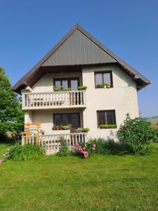 a white house with a balcony and flowers at Kovcica Rooms in Žabljak