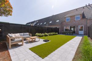 een tuin met een bank, een tafel en gras bij Modern house JULIE with spacious garden and garage in Middelkerke