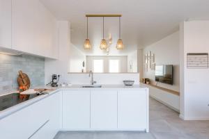 een witte keuken met witte kasten en een wastafel bij Modern house JULIE with spacious garden and garage in Middelkerke